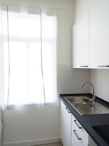 een witte keuken met een wastafel en een raam bij Herba de namorar- Céntrico apartamento en Cedeira in Cedeira