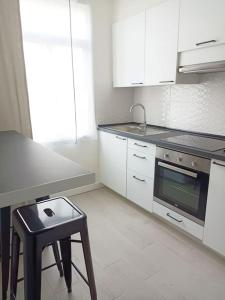 een keuken met witte kasten, een fornuis en een kruk bij Herba de namorar- Céntrico apartamento en Cedeira in Cedeira