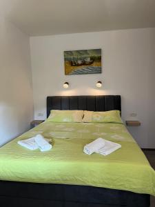 un grande letto verde con due asciugamani sopra di Apartments Vuceric a Peroj