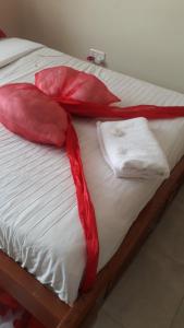 a bed with red sheets and white towels on it at Eden's Studio apartment in Syokimau