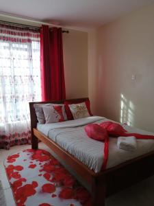 a bedroom with a bed with red pillows on it at Eden's Studio apartment in Syokimau