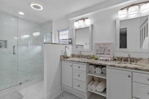 uma casa de banho branca com 2 lavatórios e um chuveiro em Theme Park Retreat 4BR near Universal Studios em Orlando