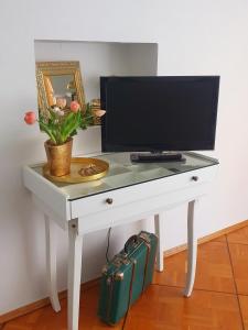 a white desk with a television and a suitcase at Kleines Domizil am Südhang in Ortenberg