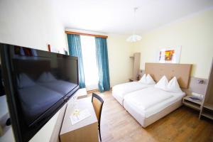een hotelkamer met een bed en een flatscreen-tv bij Hotel Lehenerhof in Salzburg