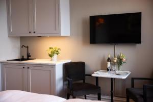 a kitchen with a table and a tv on the wall at Hotell Blanka- Lägenhet- Boutique Hotell in Varberg
