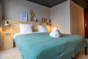 - une chambre avec un grand lit vert et 2 serviettes dans l'établissement ho36 Les Menuires, aux Menuires