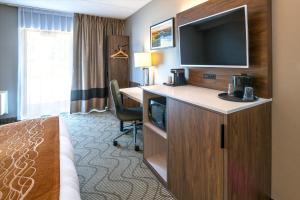 a hotel room with a bed and a desk with a television at Comfort Inn Lakeshore in North Bay