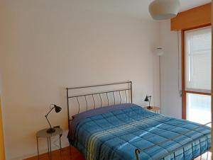 una camera da letto con un letto con un piumone blu e una finestra di Casa Sud vicino a fiera e Pordenone centro a Pordenone