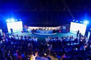 una multitud de personas sentadas en una habitación con un escenario en Mina Hotel and Residences, en Doha