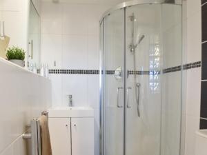 uma casa de banho branca com um chuveiro e um lavatório. em High View em Truro