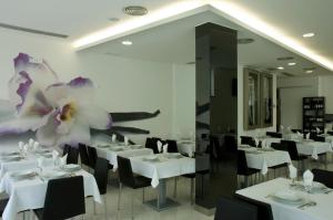 a restaurant with white tables and chairs and a flower on the wall at Hotel Genesis in Fátima