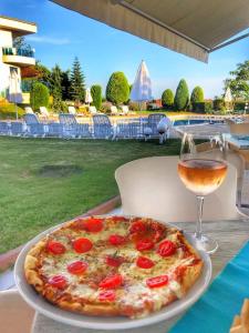 a pizza on a table next to a glass of wine at Riviera Complex 6 in Sveti Vlas