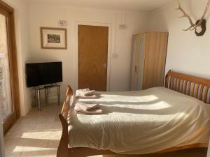 a bedroom with a bed and a flat screen tv at The Old Lookout in Osmington