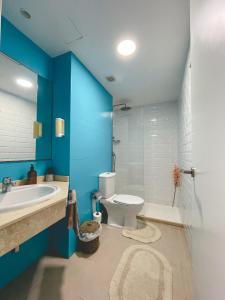 a bathroom with a white toilet and a blue wall at Seaside Apartment Corralejo : A cozy holiday home in a peaceful well located green complex in Corralejo