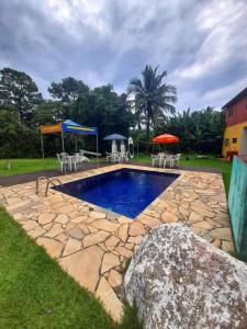una piscina con sillas y sombrillas en un patio en Chalés do Inglês, en Ilhabela