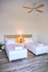2 bedden in een kamer met een plafondventilator bij View Villa in Skiathos-stad