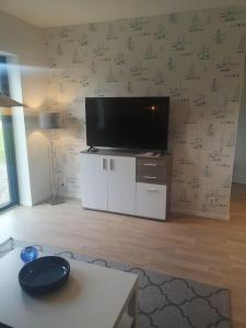 een woonkamer met een flatscreen-tv aan de muur bij Nybyggd marklägenhet strax utanför Torekov! in Båstad