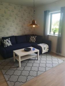 ein Wohnzimmer mit einem blauen Sofa und einem Tisch in der Unterkunft Nybyggd marklägenhet strax utanför Torekov! in Båstad