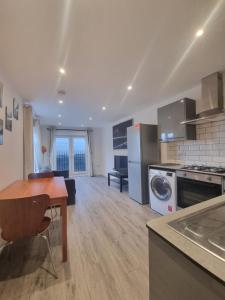 cocina y sala de estar con mesa y fogones en Comfortable Flat in SW London, en Londres