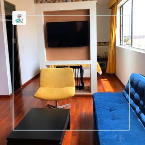 a living room with a blue couch and a tv at Hotel SJ in Mosquera