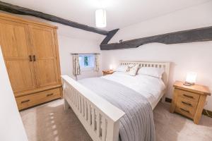 a bedroom with a white bed and a wooden cabinet at Bend or Bump Coniston in Coniston