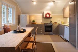 eine Küche mit einem Holztisch mit Stühlen und einem Tisch sidx sidx sidx in der Unterkunft Smørøyet. Sentral beliggenhet på Geilo. in Geilo