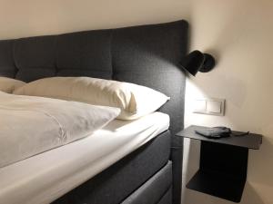 a bed with a black headboard next to a side table at kleines Stadthaus in Isny im Allgäu