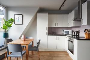 a kitchen with white cabinets and a wooden table at Holborn by Viridian Apartments in London