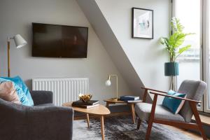 ein Wohnzimmer mit einem TV, 2 Stühlen und einem Tisch in der Unterkunft Holborn by Viridian Apartments in London