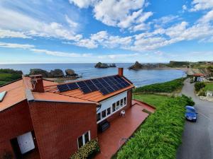 a house with solar panels on top of it next to the ocean at 5 bedrooms house at Liencres 50 m away from the beach with sea view sauna and enclosed garden in Liencres