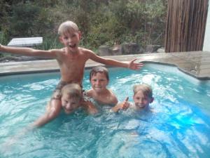 Tres niños en una piscina en Plettenberg Bay Cottage, en Plettenberg Bay