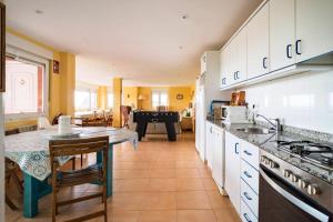 uma cozinha com uma mesa e um fogão forno superior em 5 bedrooms house at Liencres 50 m away from the beach with sea view sauna and enclosed garden em Liencres