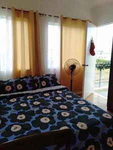 a bedroom with a bed with a blue comforter with flowers at Avida 3-Bedroom Vacation House with Pool in Minuluang