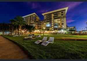 a group of chairs sitting in the grass in front of a building at One-bed apartment at Darwin Waterfront Precinct in Darwin