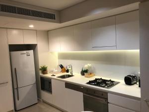 een keuken met witte kasten en een witte koelkast bij One-bed apartment at Darwin Waterfront Precinct in Darwin