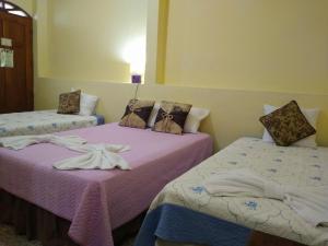 two beds in a room with purple sheets at Guest House Los Corredores del Castillo in Granada