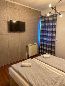 two beds in a room with a tv on the wall at Prenociste Lane in Ključ