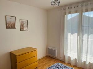 - une chambre avec une commode et une grande fenêtre dans l'établissement Appartement, à Pierrelatte