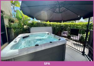 a hot tub on a balcony with an umbrella at Park View On Bayswater | 2 Storey Townhouse in Aitkenvale