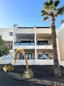 a white building with palm trees in front of it at Al Sole Studios residence Playa Roca in Costa Teguise