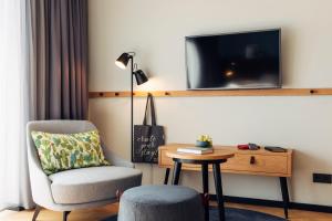 Habitación con silla, mesa y TV. en harry's home hotel & apartments, en Villach