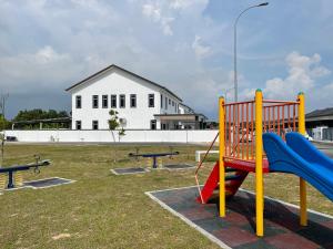 um parque infantil com escorrega e bancos num parque em cuti-cuti port dickson homestay em Porto Dickson