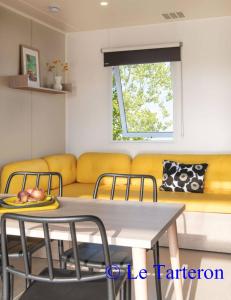 a living room with a table and a yellow couch at Camping Le Tarteron in Le Crotoy