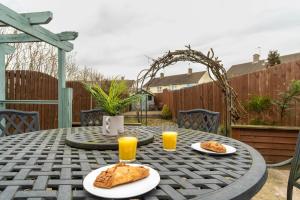 una mesa con dos platos de comida y dos vasos de zumo de naranja en Flamingo Retreat, en Leicester