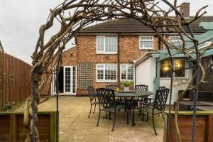 un patio con mesa y sillas frente a una casa en Flamingo Retreat, en Leicester