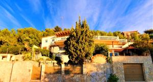 uma casa com uma árvore em frente a uma cerca em Ashram Villa Sunshine em Sitges