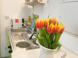 a vase filled with orange and yellow tulips on a kitchen counter at Ferienzimmer Adalonia in Greifswald