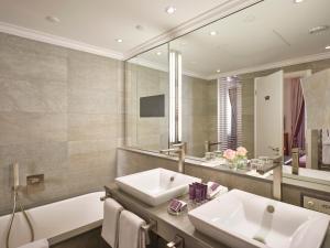 a bathroom with a sink and a tub and a mirror at The Dufour by Hotel Schweizerhof Zürich in Zurich