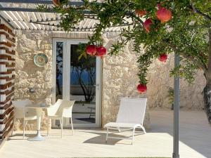 a patio with white chairs and a table and a tree at Daedalium in Marina di Palma