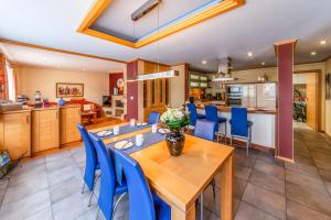 una cucina e una sala da pranzo con tavolo in legno e sedie blu di Ferienhaus CAMILLO a Bullange/Büllingen